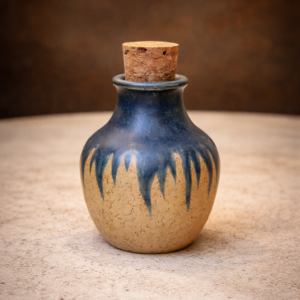 Hand-thrown ceramic jar with a natural cork stopper and blue dripping glaze over speckled clay by Corax Ceramics.